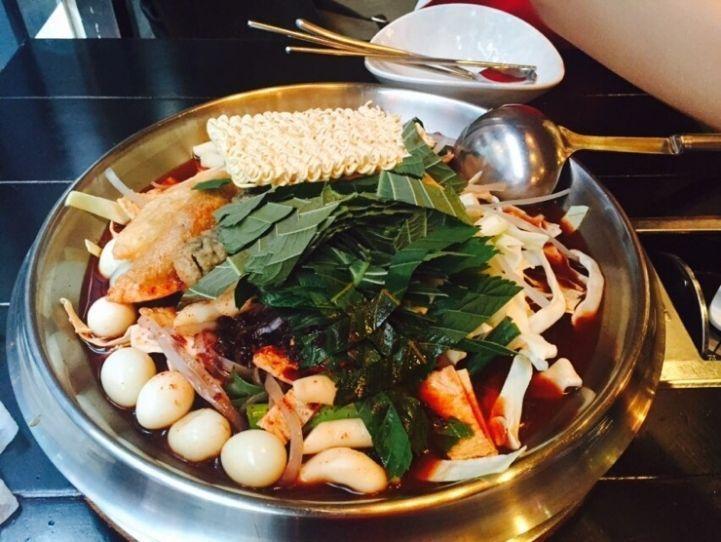 Freshly served instant Tteokbokki at Hwa Tteok, filled with ramen, eggs, and spicy sauce amidst a lively and aromatic setting.